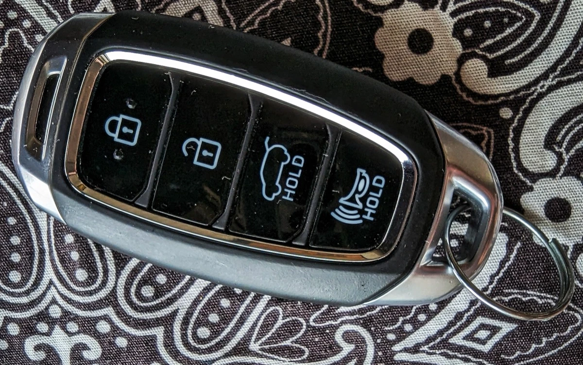 A Hyundai smart key fob with lock, unlock, trunk and panic buttons lying on a patterned cloth.